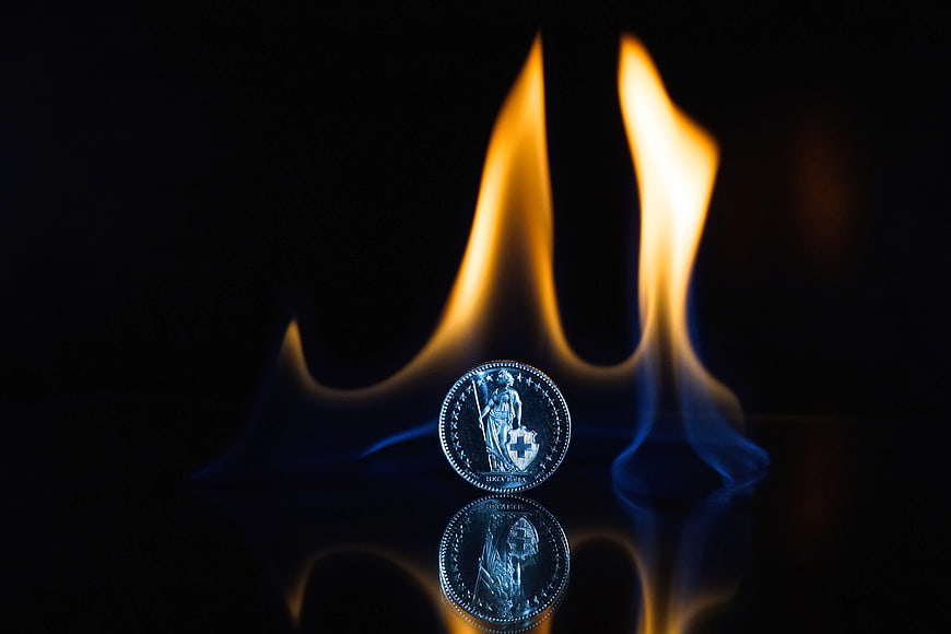 Silver Coin with Flame on Black Reflective Surface