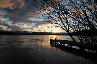 Silhouette of wooden dock on frozen lake at sunset