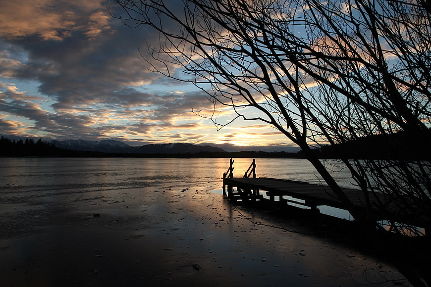 Silhouette of wooden dock on frozen lake at sunset