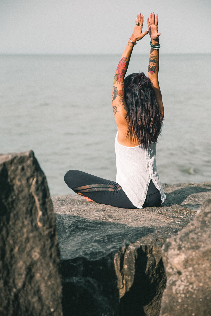 Woman Practicing Yoga on Rocks by the Ocean