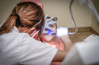Dentist curing filling on child patient with blue light
