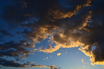 Dramatic sunset clouds with golden light against deep blue sky