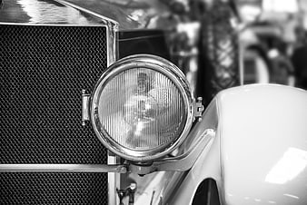 Close-up of vintage car headlight and grille in black and white