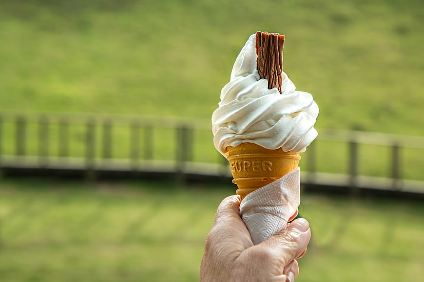 Hand Holding Vanilla Soft Serve Ice Cream Cone Outdoors