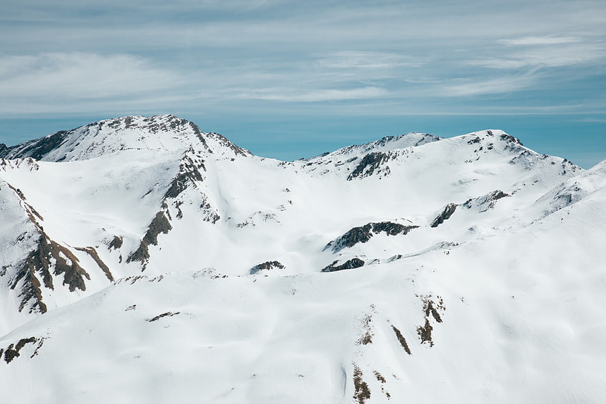 Snow-covered mountain peaks with blue sky and clouds