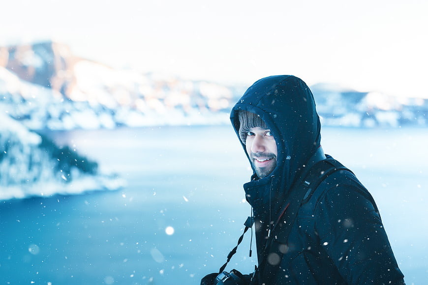Happy male photographer in winter snow with camera