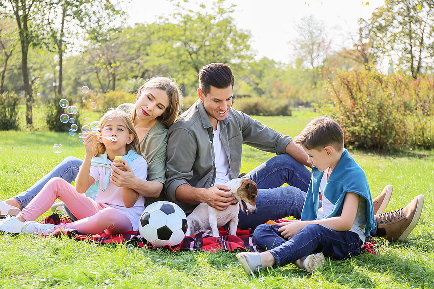 Happy family with dog having picnic in park