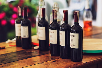 Row of red wine bottles on rustic wooden table