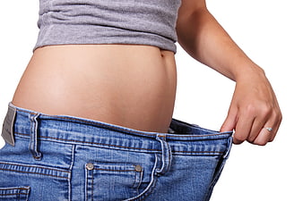 Woman pulling loose jeans waistband to show weight loss