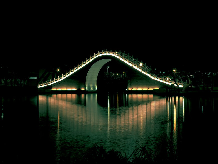Illuminated arch bridge reflection in water at night