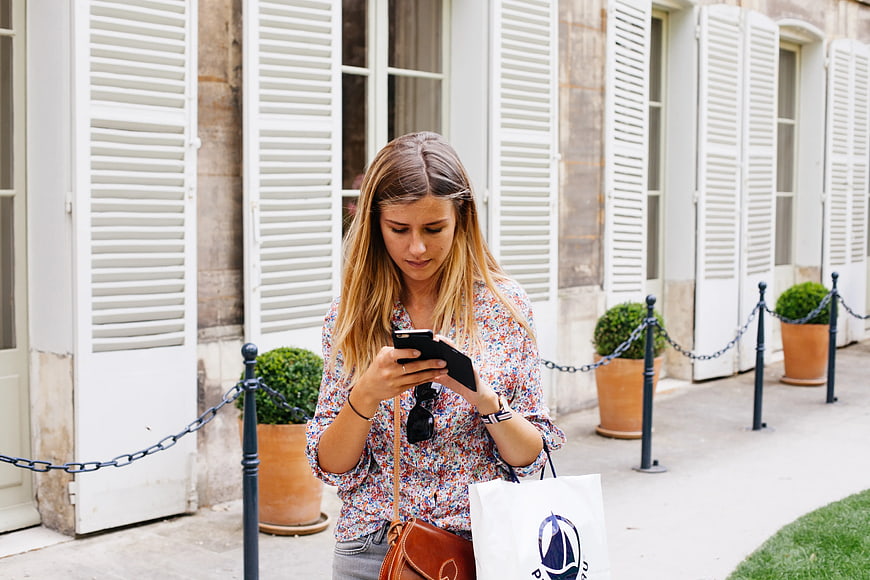Woman checking smartphone while shopping on European street