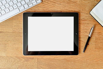 Top view of tablet with blank screen on wooden desk