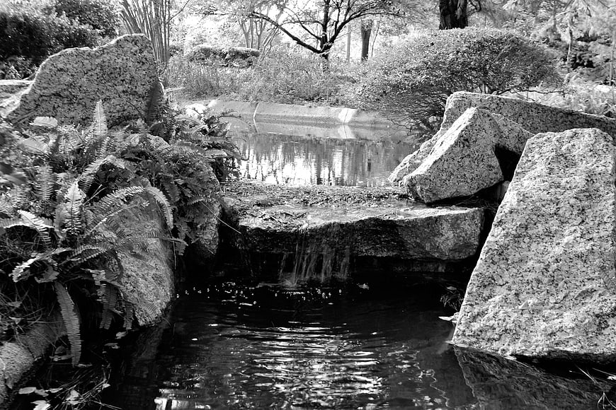 Black and white stream with waterfall and rocks in a park