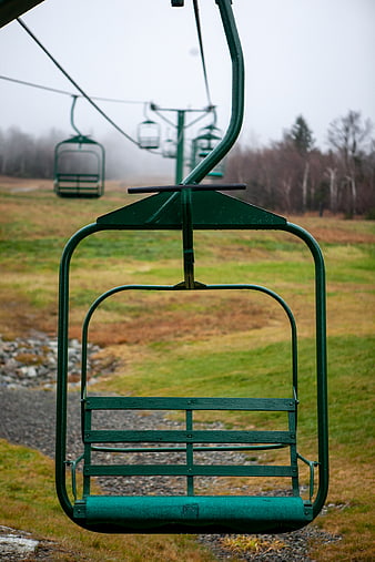 Empty green ski lift chair on foggy mountain slope
