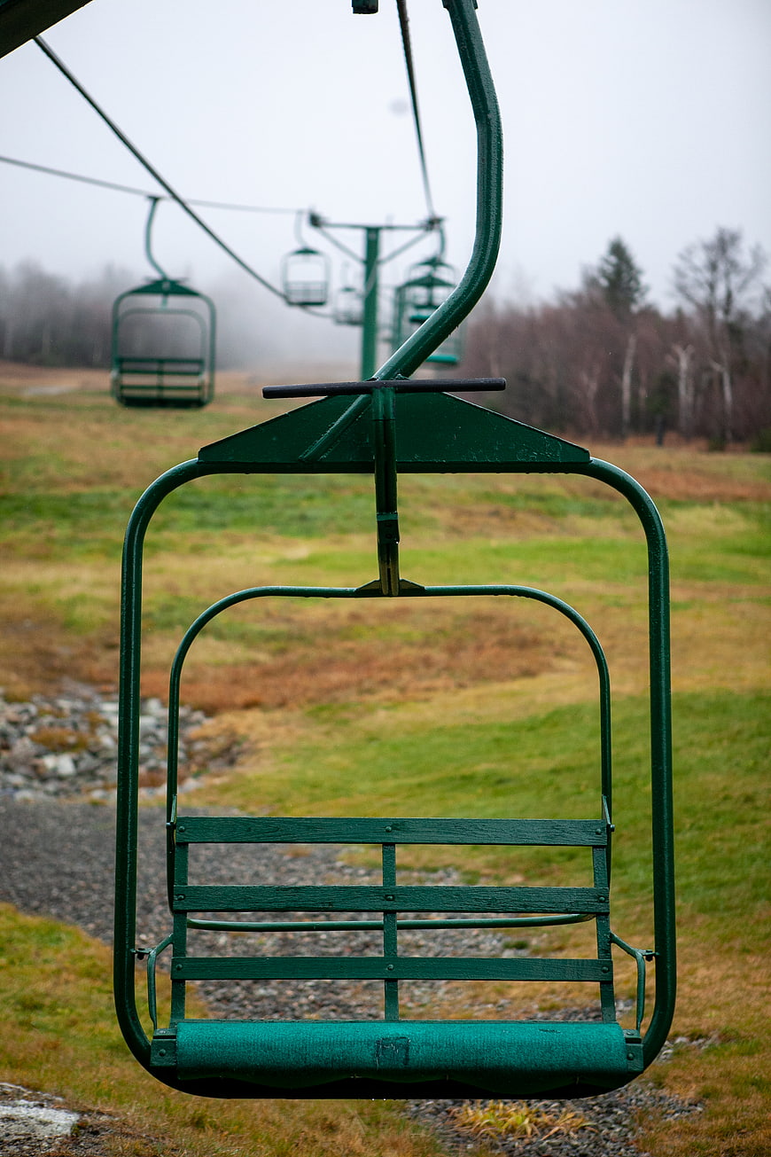 Empty green ski lift chair on foggy mountain slope