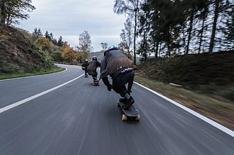 Skateboarders Downhill on Winding Forest Road
