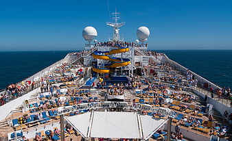 Busy cruise ship deck with water slide and ocean view