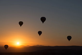 Silhouetted Hot Air Balloons at Sunset Over Mountains