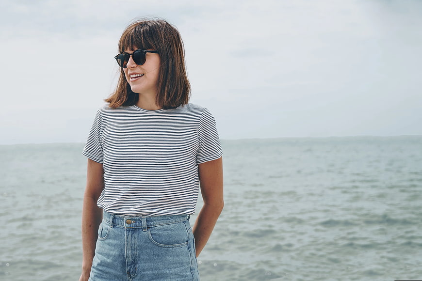 Smiling Woman in Striped Shirt and Sunglasses by the Sea