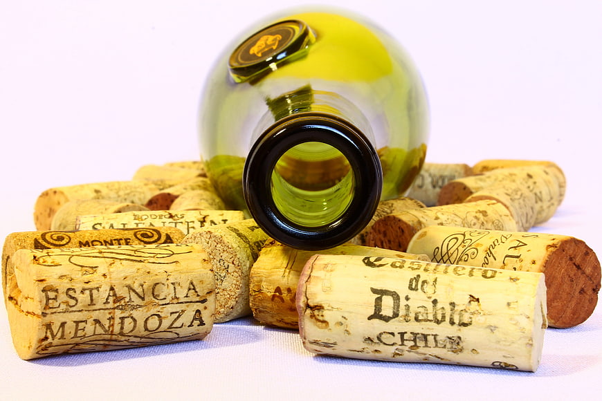 Empty wine bottle lying on pile of wine corks