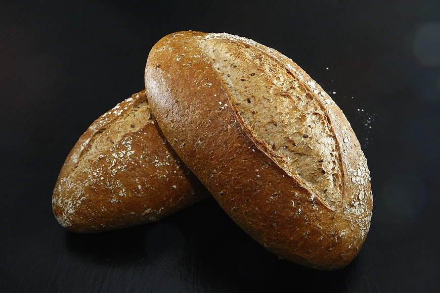 Two loaves of rustic artisan bread on dark background
