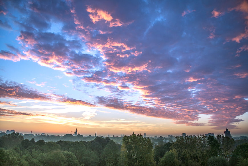 Dramatic pink and blue sunrise clouds over city skyline