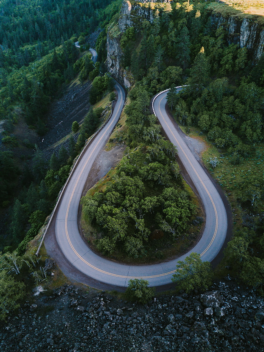 Aerial View of Winding Mountain Road Through Forest