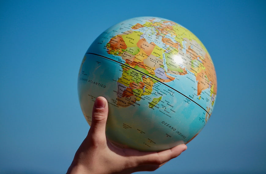 Hand holding globe against blue sky background