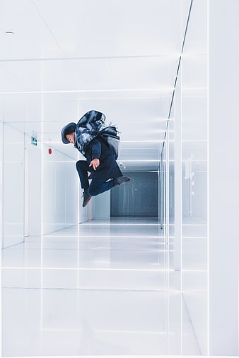 Man jumping in futuristic white hallway with neon lights