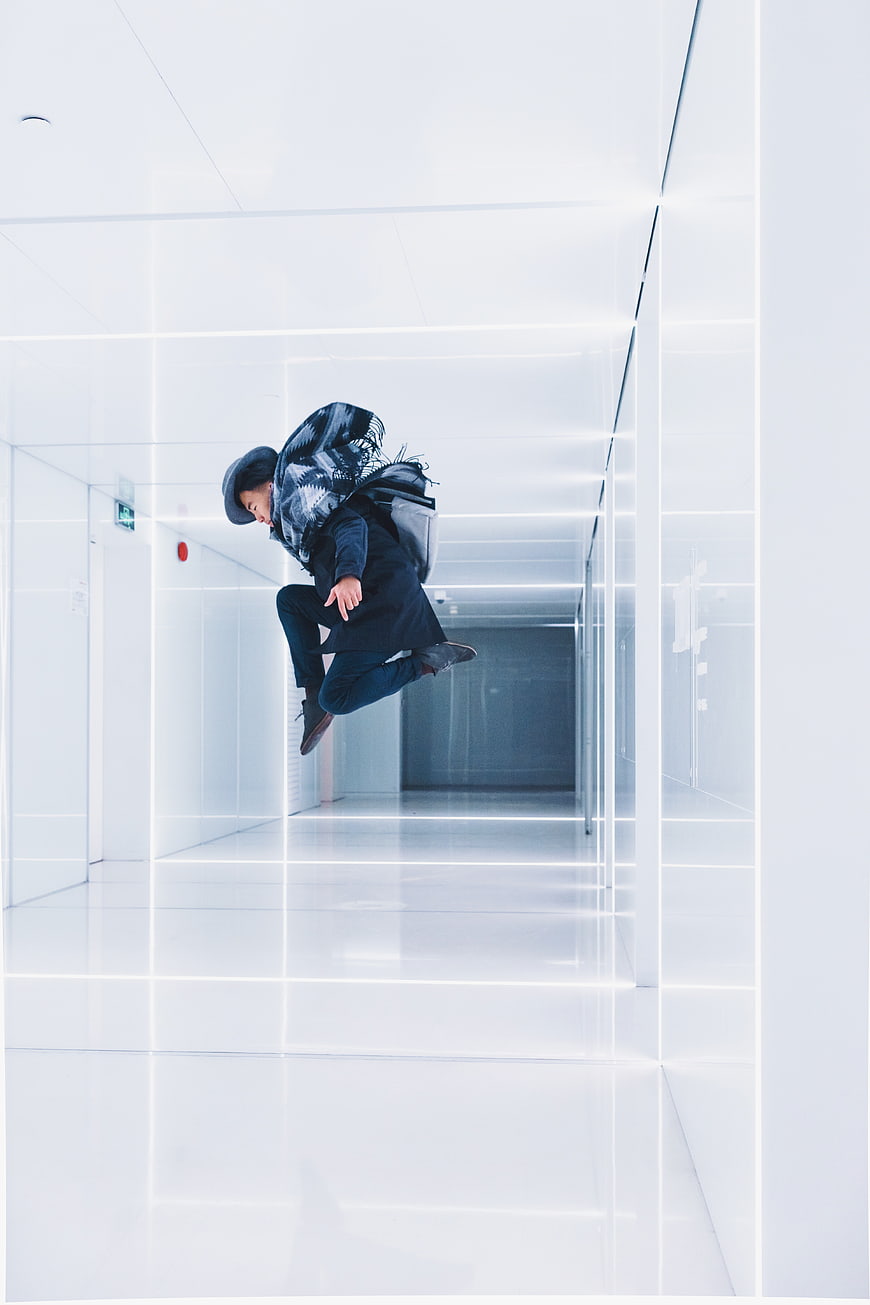 Man jumping in futuristic white hallway with neon lights