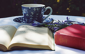 Vintage teacup, open book, and purple flowers on a white table
