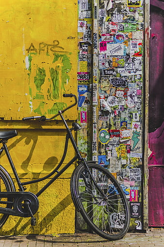 Black Bicycle Leaning Against Vibrant Yellow Graffiti Wall