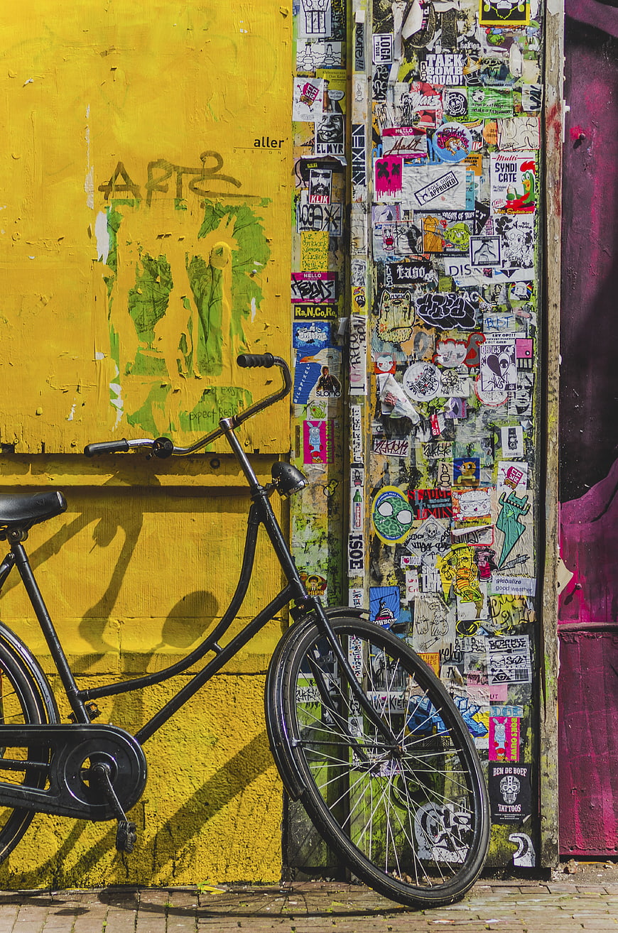 Black Bicycle Leaning Against Vibrant Yellow Graffiti Wall