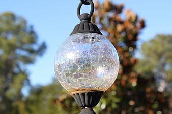 Close-up of cracked glass outdoor lantern against blue sky