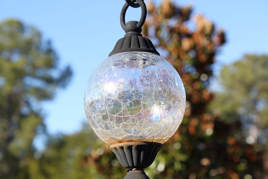 Close-up of cracked glass outdoor lantern against blue sky