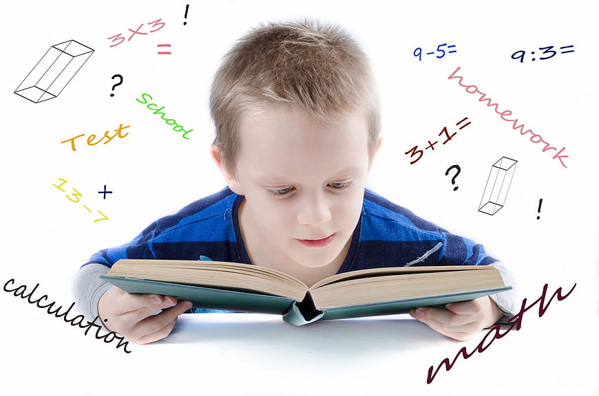 Young boy reading book with floating math equations and school words