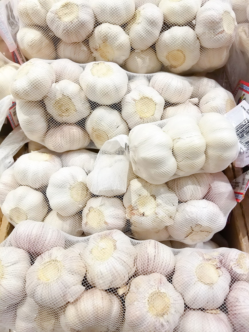 Fresh garlic bulbs in mesh bags at market