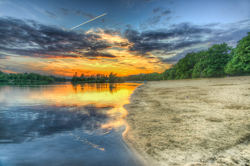 Dramatic sunset over lake with sandy beach and clouds
