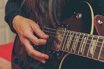 Close-up of woman playing electric guitar with pick