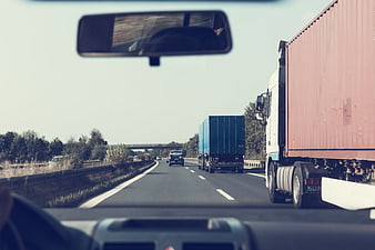 Highway driving view with trucks and rearview mirror