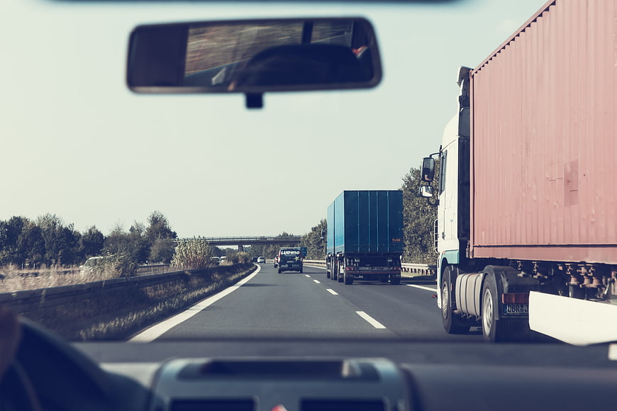 Highway driving view with trucks and rearview mirror