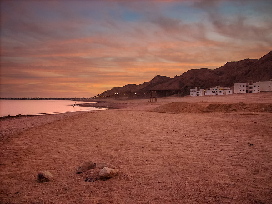 Sunset Landscape of Dahab Beach with Mountains and Buildings