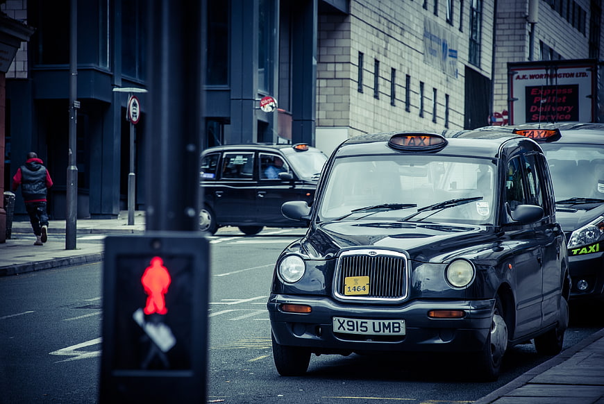 Black London Taxi Cab on Urban Street with Red Traffic Light