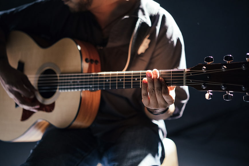 Close-up of man playing acoustic guitar in studio