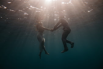 Romantic couple holding hands underwater in the ocean