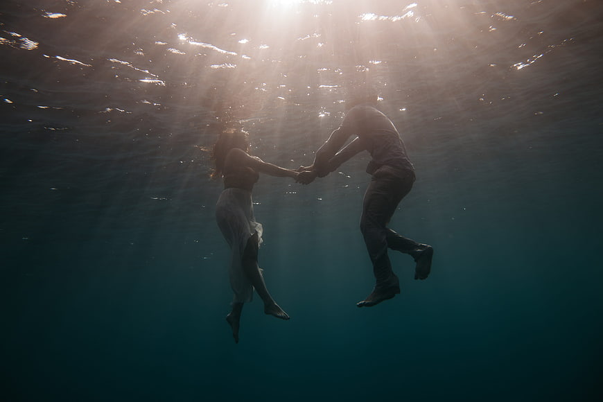 Romantic couple holding hands underwater in the ocean