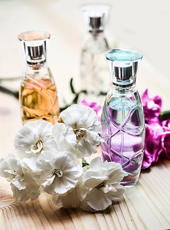Elegant Perfume Bottles with White and Purple Flowers on Wooden Surface