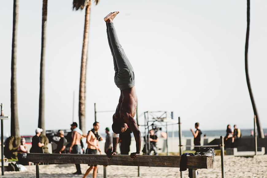 Athletic Man Performing Handstand on Beach Bench