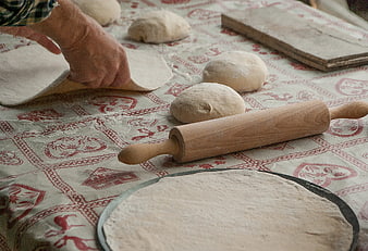 Hands Rolling Out Dough on Patterned Tablecloth