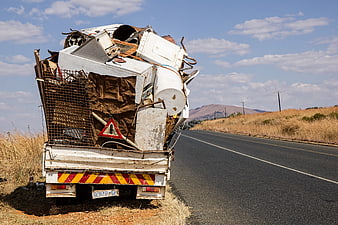 Overloaded scrap metal truck parked on rural road